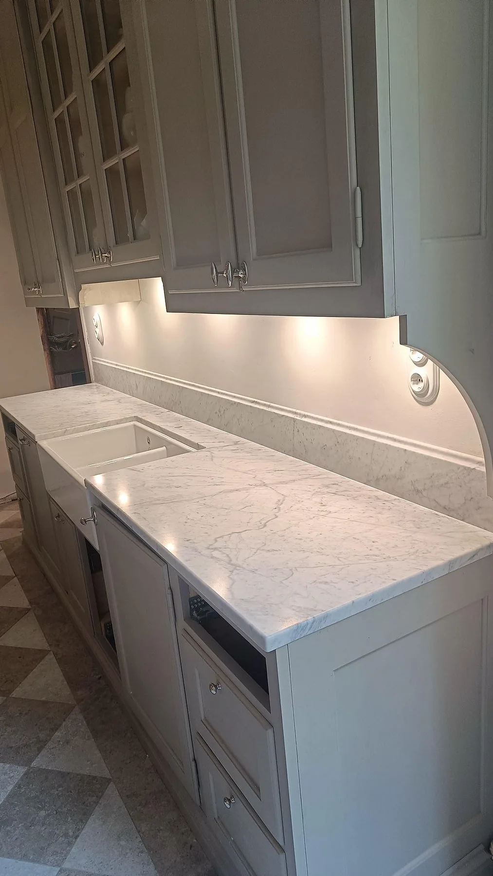 Matt köksbänkskiva i Carrara C marmor med vit porslinsho, låg stänkkant och grå träinredning i Malmö.