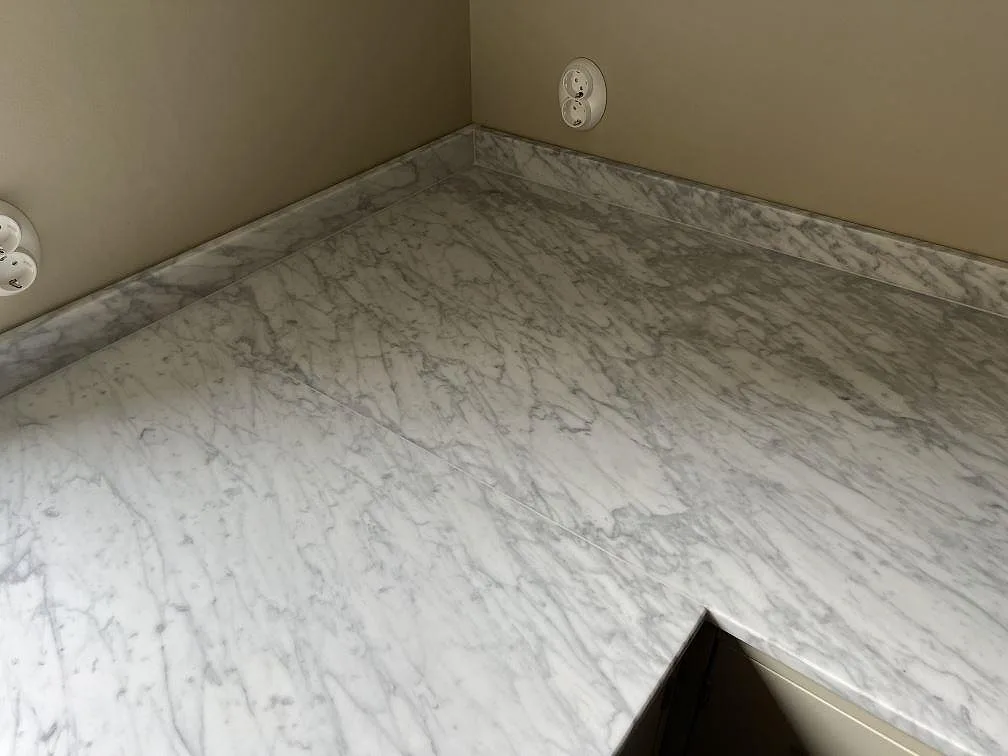 Hörn i U-kök med köksbänkskiva och stänkkant i matt Carrara C marmor i Malmö.