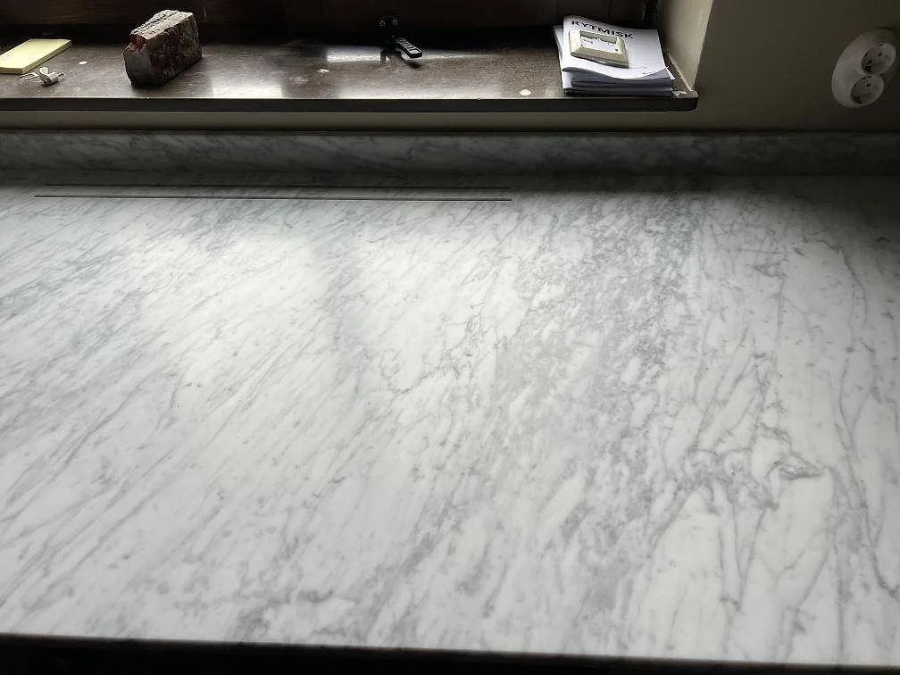 Fönstersida med installerad köksbänkskiva i matt Carrara C marmor och låg stänkkant i Malmö.