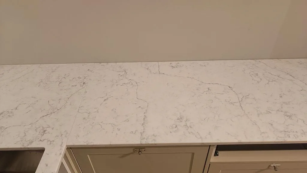 Rak väggbänk i polerad Carrara C marmor med synlig skarv och öppen köksinredning under montering i Rydebäck.