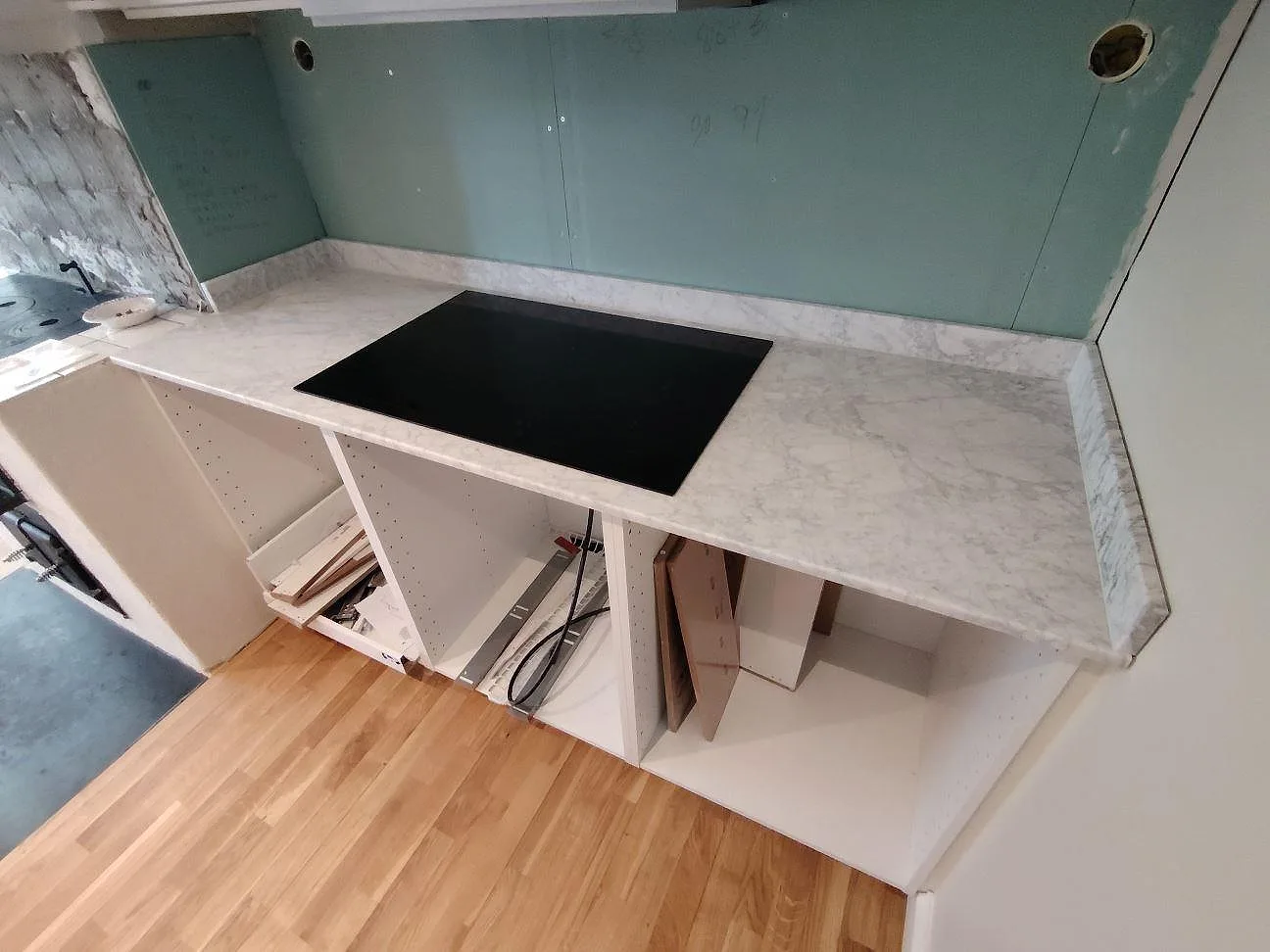 Köksbänkskiva i matt Carrara C marmor med svart häll och låg stänkkant i Saltsjö Boo.