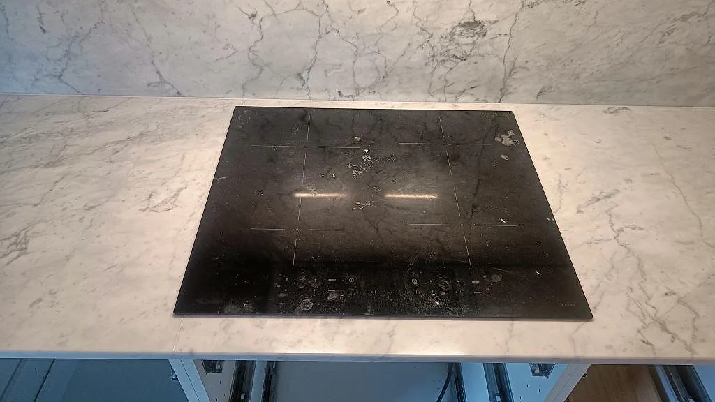 Induktionshäll infälld i en polerad Carrara C köksbänkskiva med vit marmorådring i Skee.