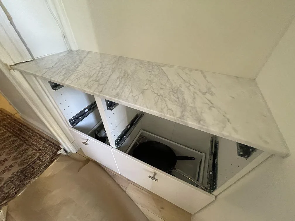 Rak bänkskiva i matt Carrara C marmor med grå ådring och väggnära passning i ett kök i Stockholm.