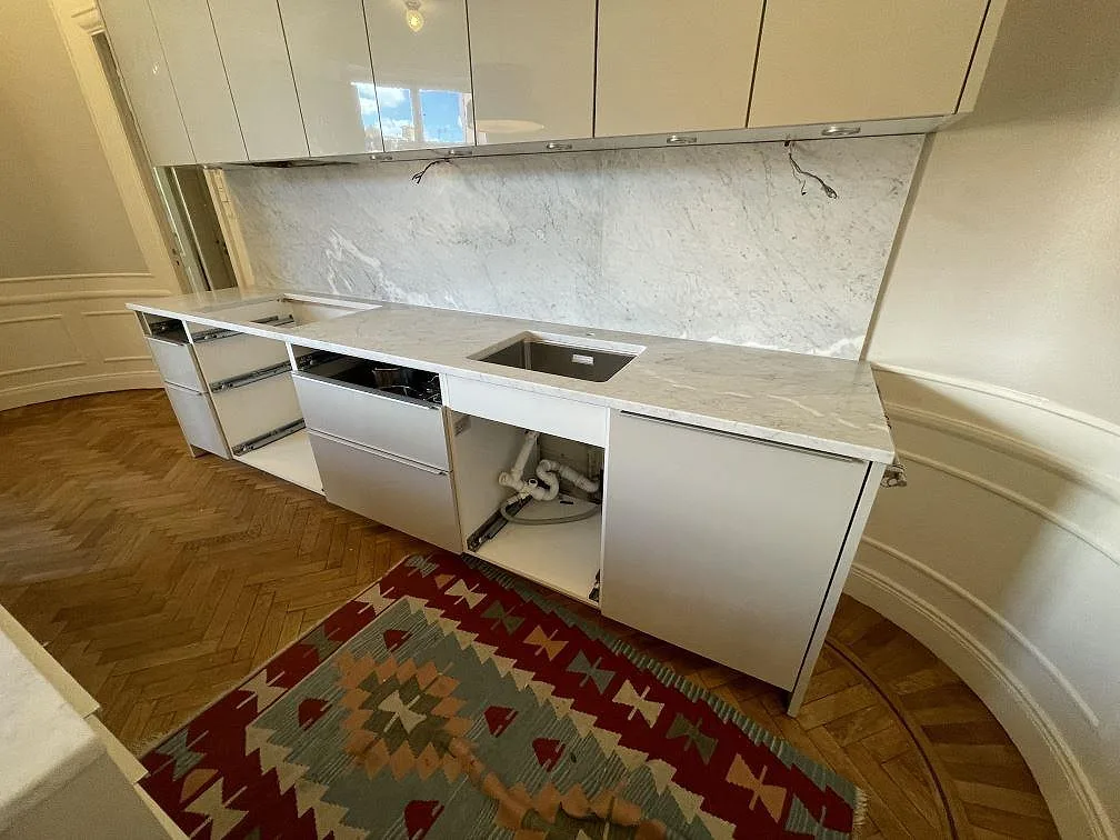 Köksbänkskiva i matt Carrara C marmor med diskho, hälluttag och hög stänkvägg i Stockholm.