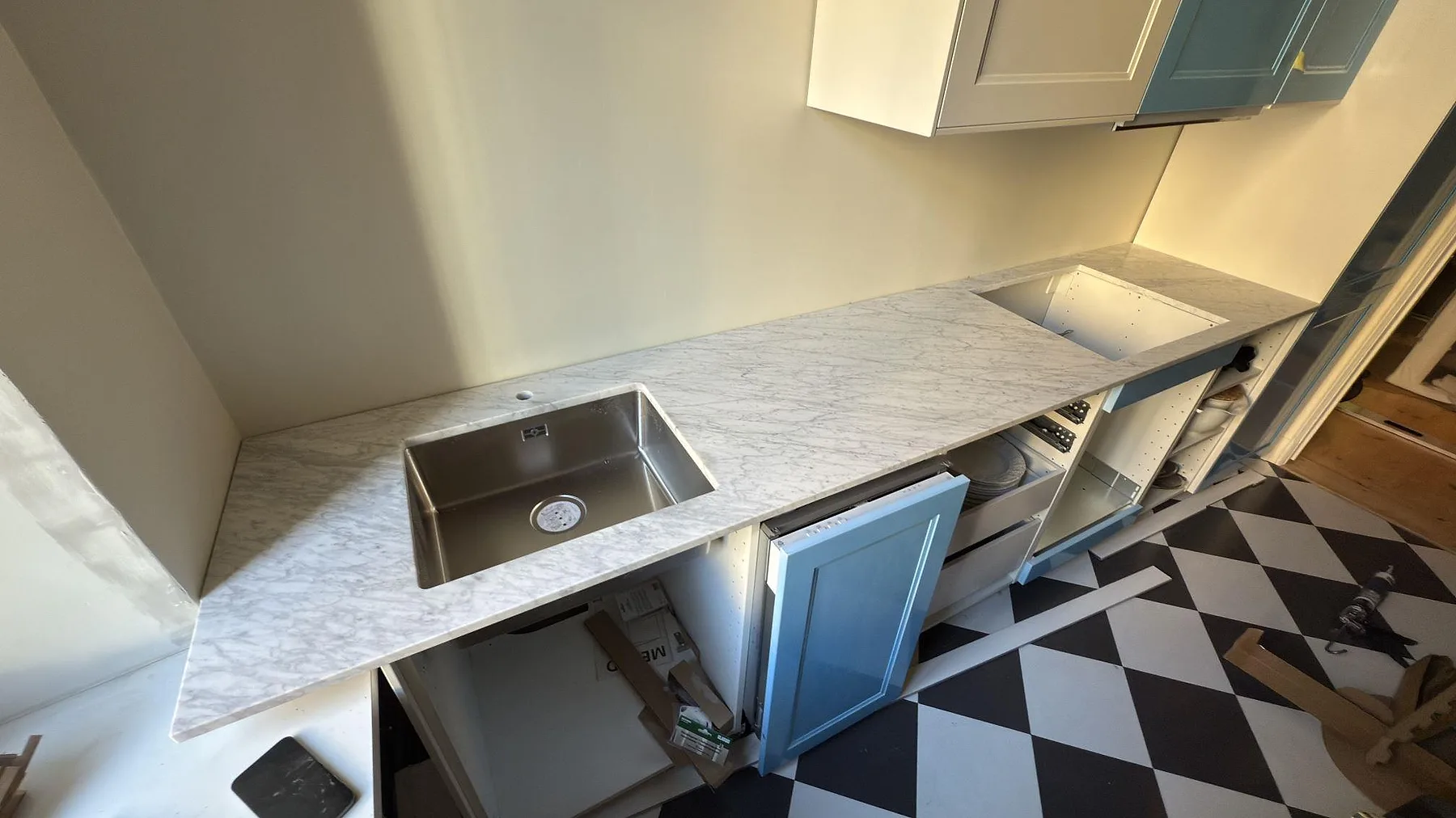 Köksbänkskiva i 20 mm matt Carrara C, marmor, med synlig diskho och ett större urtag i ett kök i Stockholm.