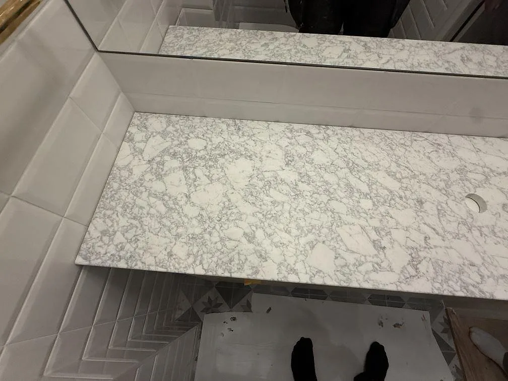Sidovy av installerad Carrara C marmorskiva i badrum i Stockholm, matt yta med ljus bas och grå ådring.