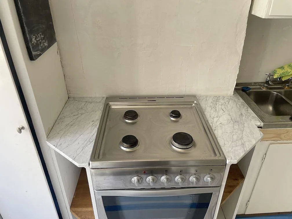 Köksbänkskiva i polerad Carrara C marmor, 20 mm, runt en fristående spis i ett kompakt kök i Sundbyberg.