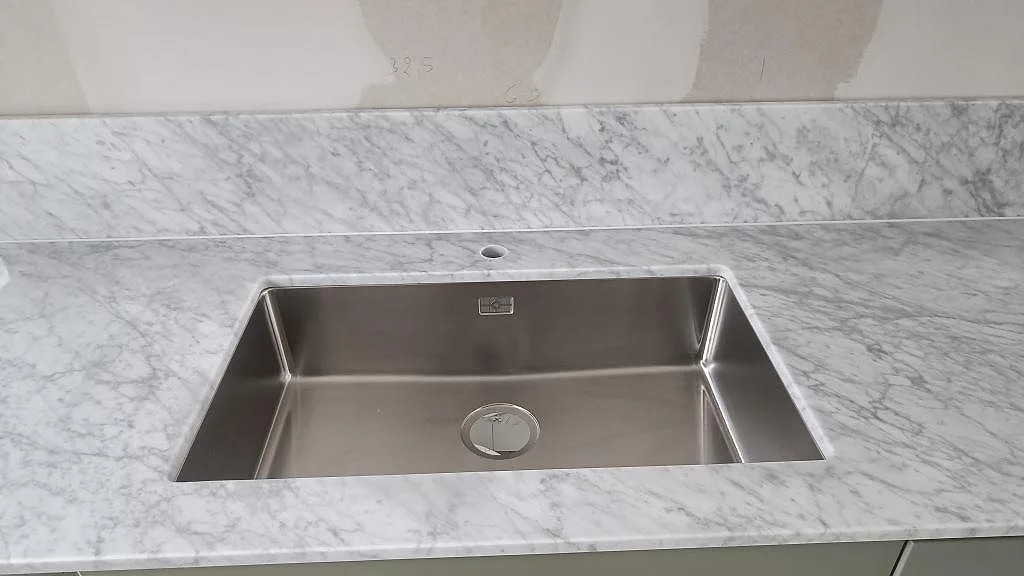 Underlimmad rostfri diskho i Carrara C marmorbänkskiva med uppvikt stänkkant och grå ådring i Svanshall.