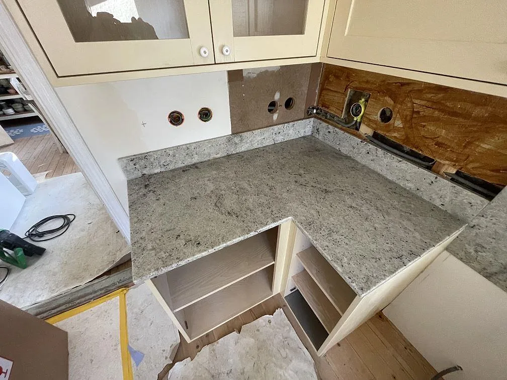 Polerad Colonial White-granit sedd uppifrån med tydlig ådring och stänkkant längs väggen i ett kök i Östra Sönnarslöv.