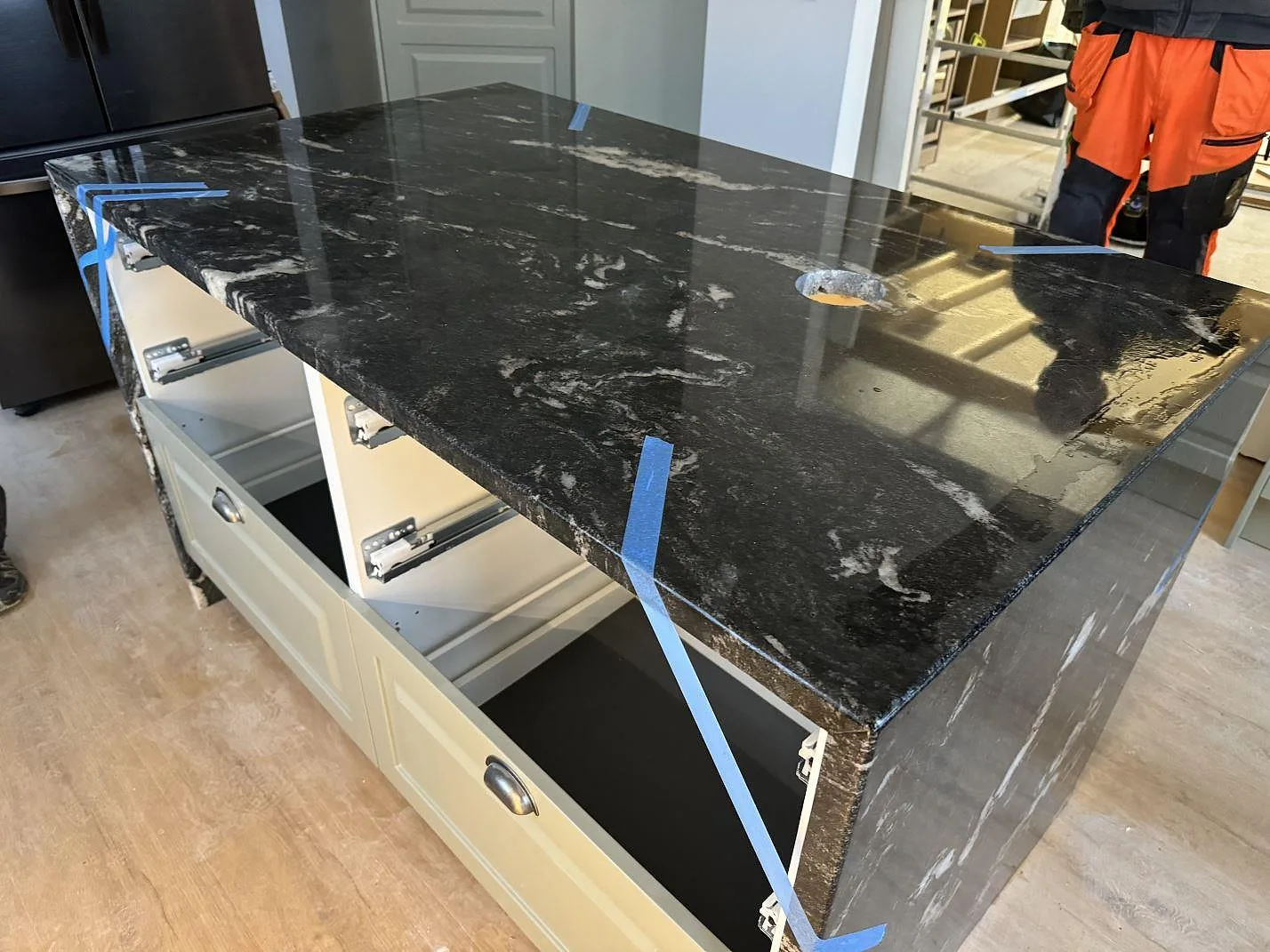 Köksö i polerad Cosmic Black granit med svart yta och ljus ådring under montering i ett kök i Älmhult.
