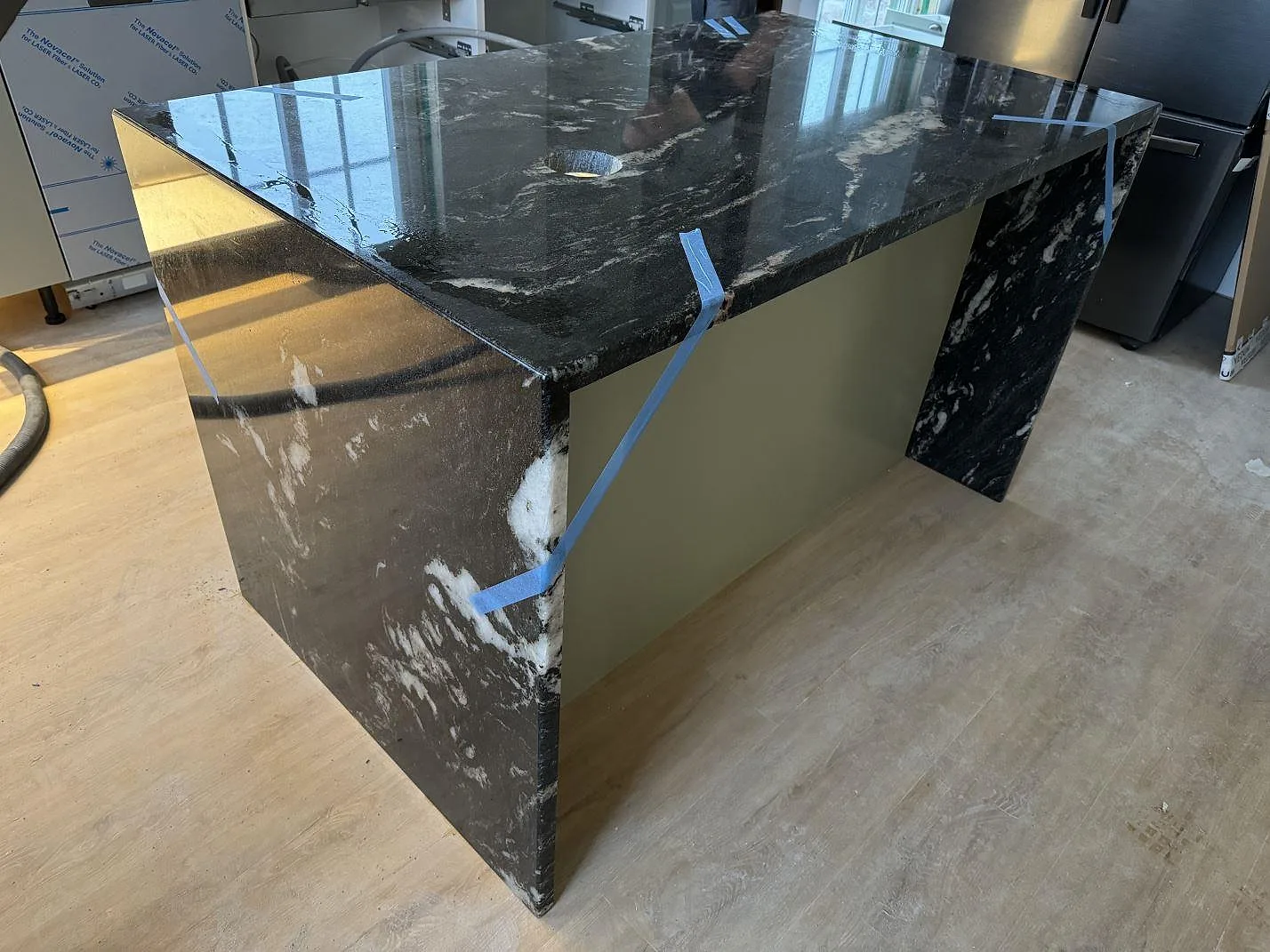 Polerad köksö i Cosmic Black granit med vattenfallsidor och synliga vita ådror i ett kök i Älmhult.