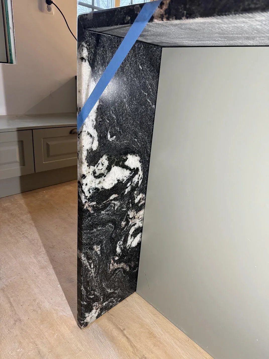 Detalj av polerad Cosmic Black granit vid köksö och väggbänk med tydlig svartvit ådring i Älmhult.