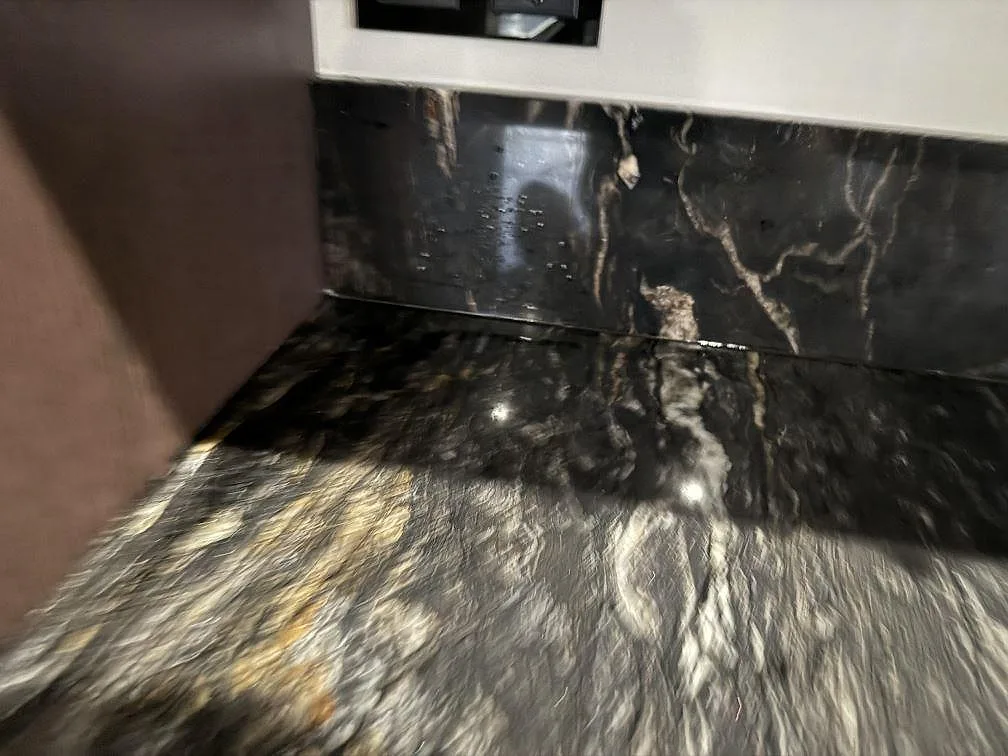 Närbild av polerad Cosmic Black granit med blank yta, ljusa mineralstråk och stänkskydd i ett kök i Grebbestad.