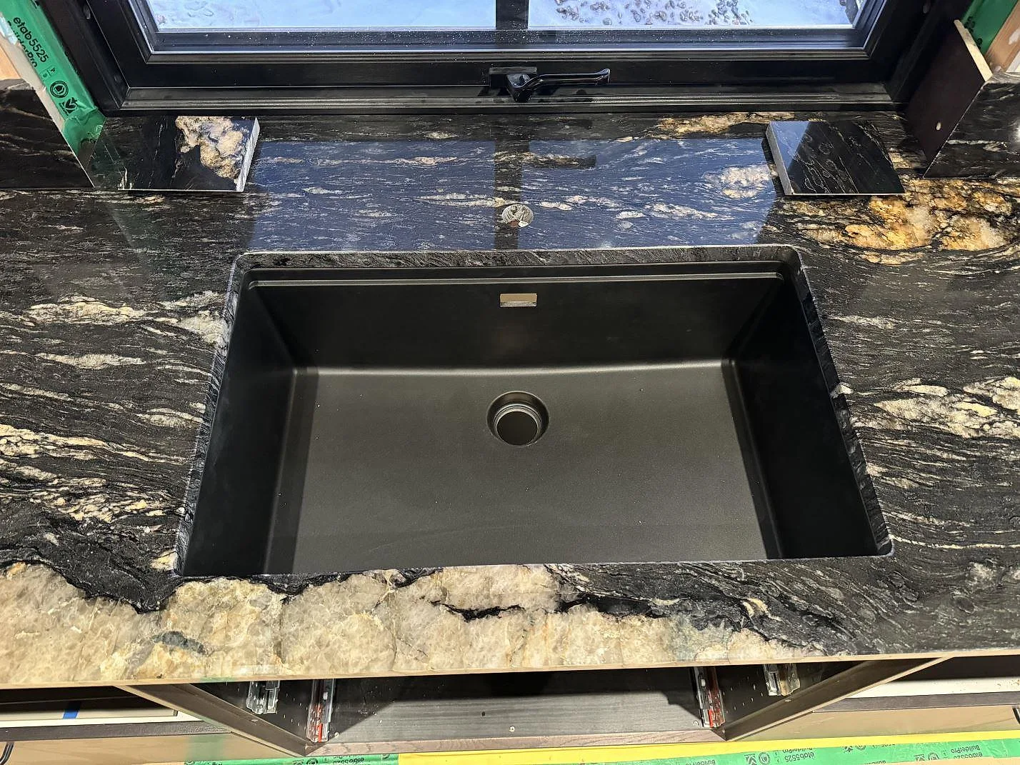 Underlimmad svart diskho i polerad Cosmic Black granit med fönster bakom och tydlig naturstensådring i Grebbestad.