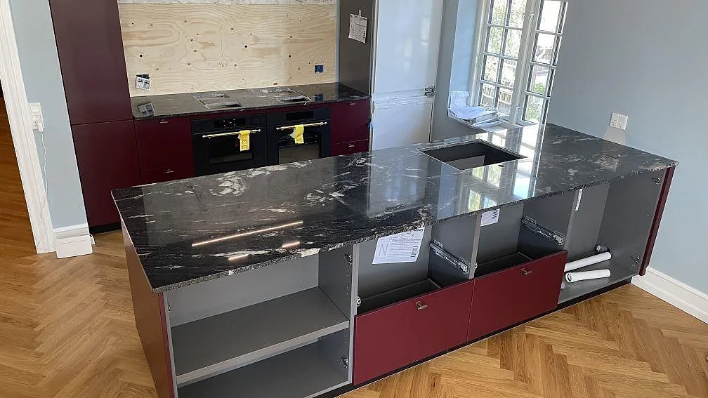 Polerad köksbänkskiva i Cosmic Black granit med köksö och bakre arbetsyta i ett kök i Hellerup.