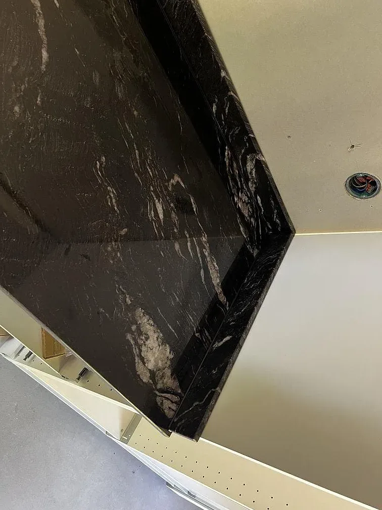 Bänksträcka i polerad Cosmic Black granit med uppvikt stänkkant mot vägg i Höganäs.