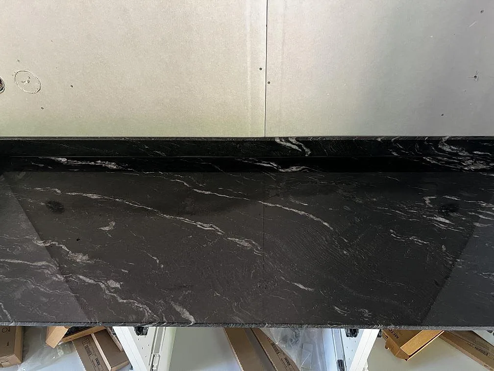 Rak köksbänkskiva i polerad Cosmic Black granit med stänkkant längs väggsidan i Höganäs.