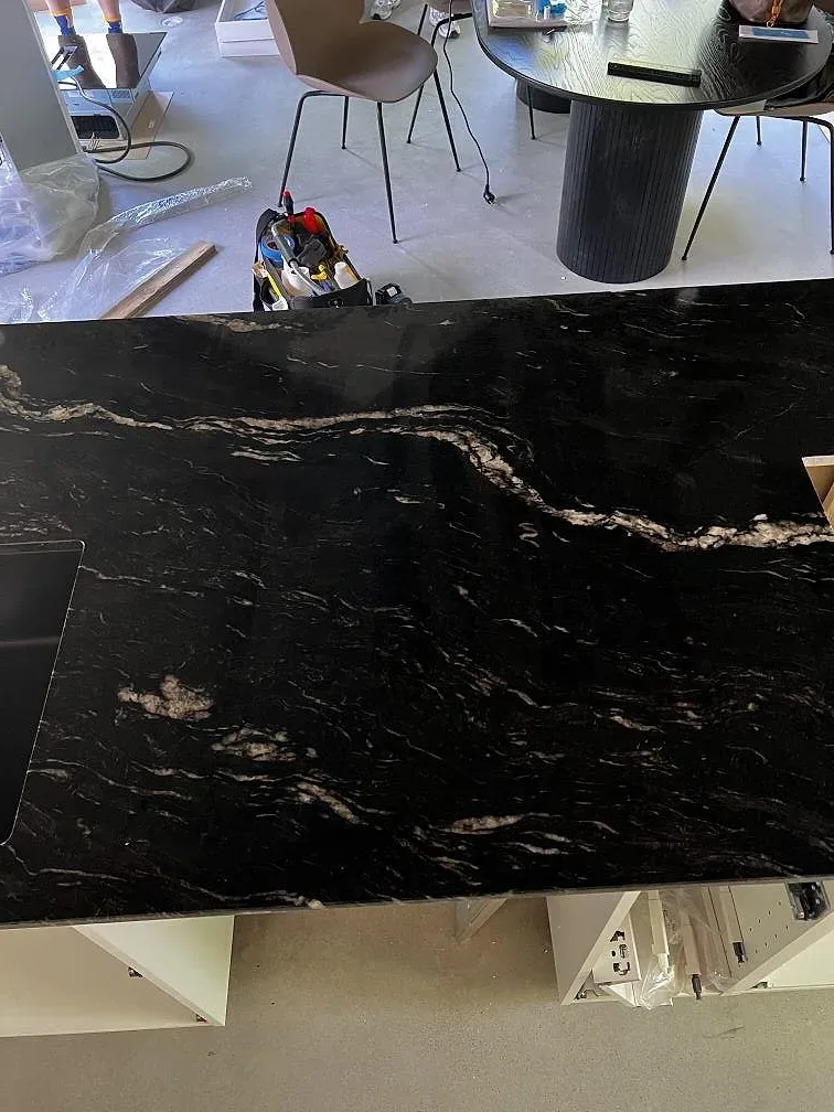 Närbild av ådringen i polerad Cosmic Black granit på en köksö med öppning i Höganäs.