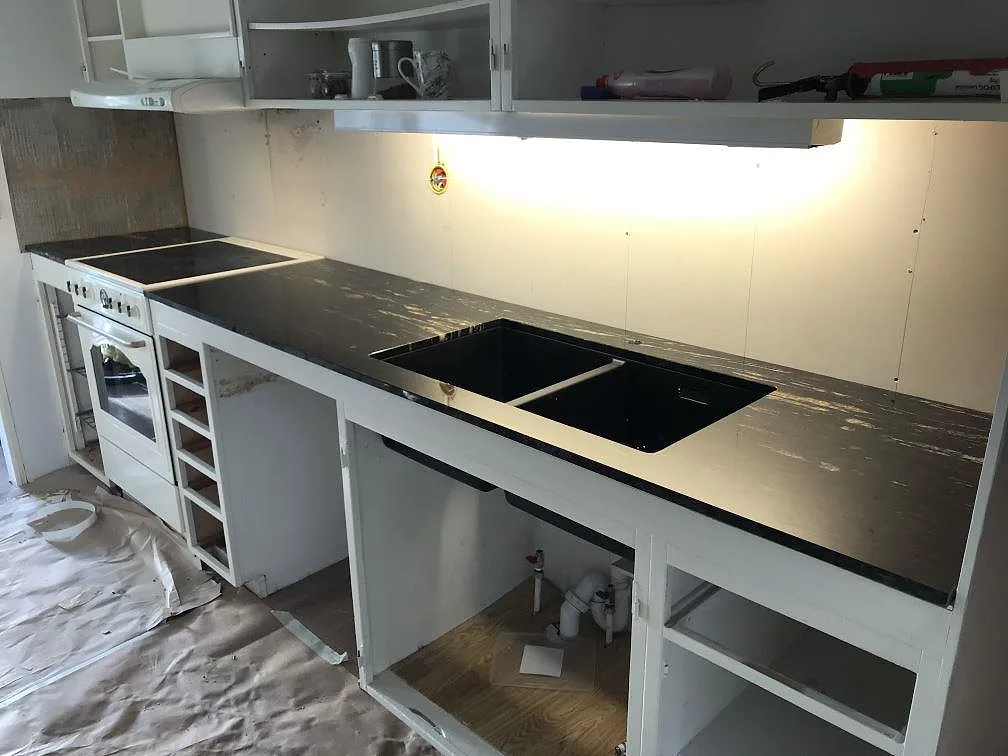 Installerad köksö i polerad Cosmic Black granit på vit stomme, fotograferad uppifrån i ett kök i Hultsfred.