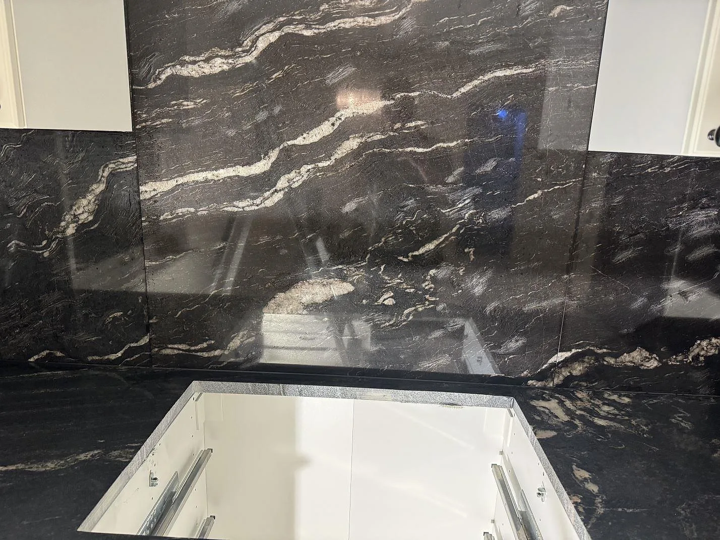 Köksbänkskiva i Cosmic Black granit med stor öppning och blank väggbeklädnad bakom arbetsytan i Malmö.