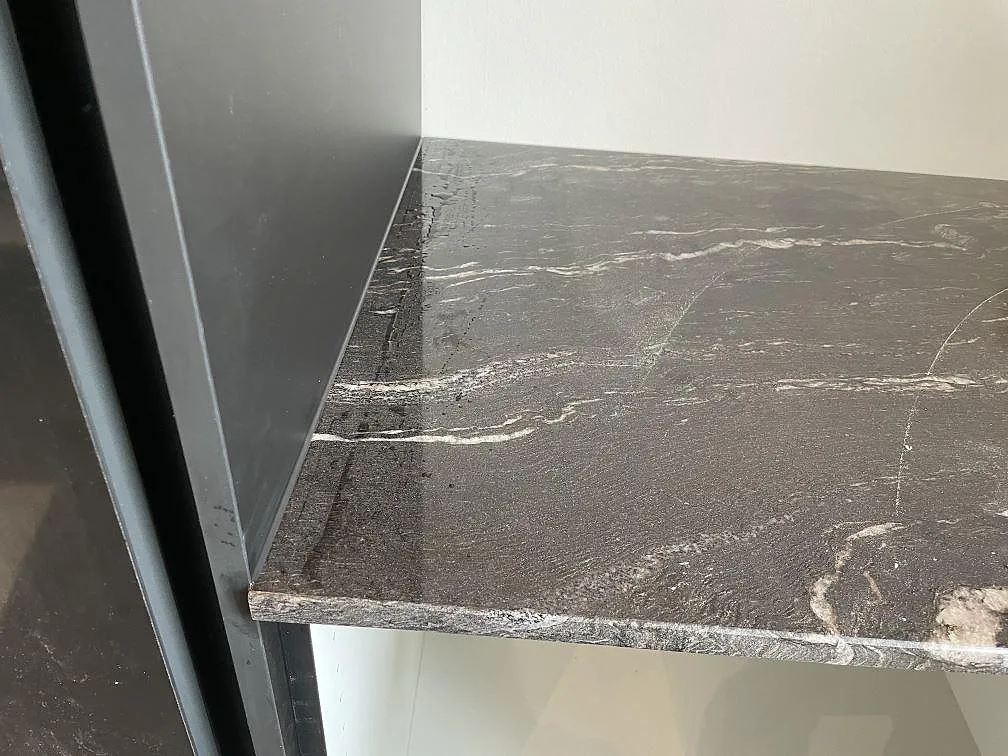 Kantdetalj av polerad Cosmic Black granit monterad mot högskåp i ett kök i Tølløse.