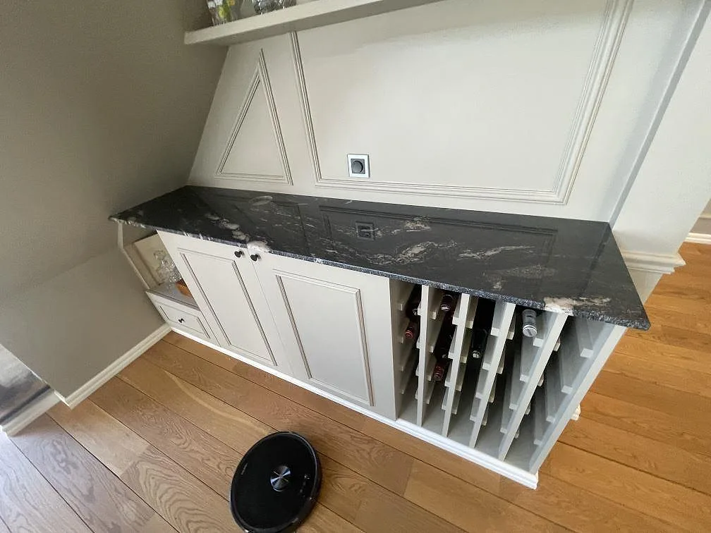 Granitbänkskiva i Cosmic Black, polerad, monterad på vit inredning med väggpanel i Upplands väsby.