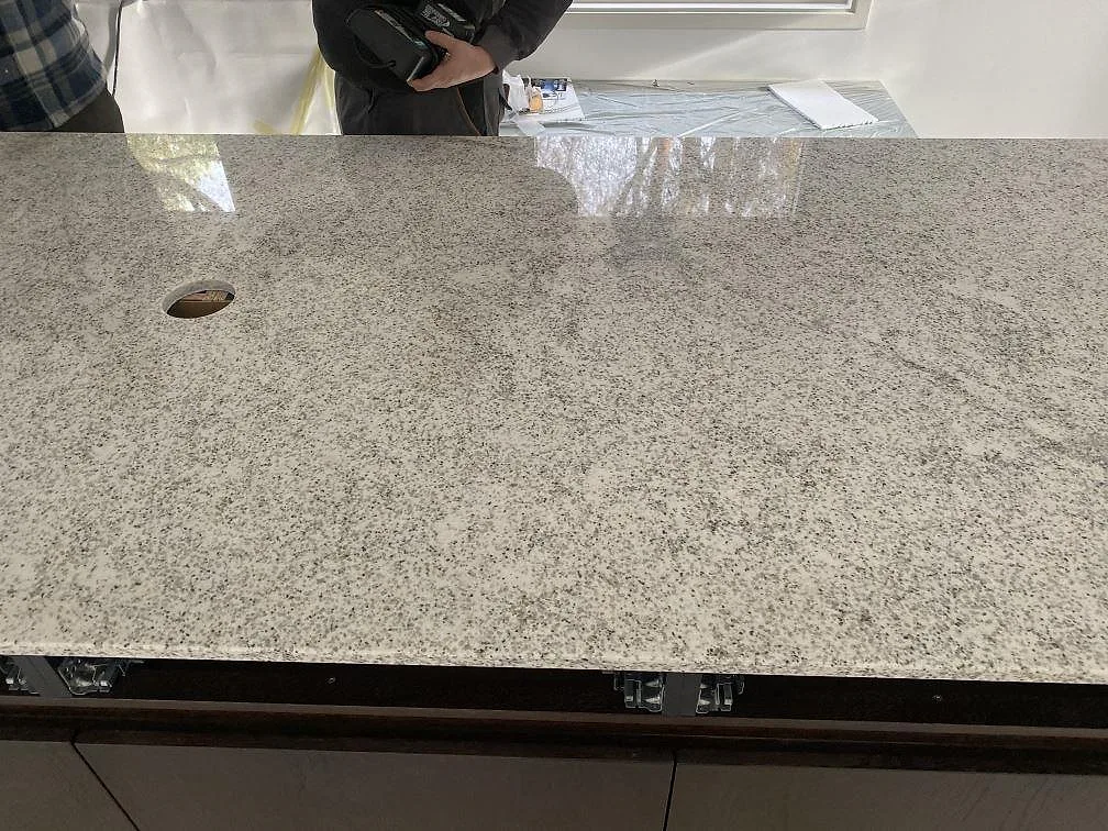 Detalj av köksö i polerad Cotton White granit med tät grå och svart kornteckning i Höllviken.