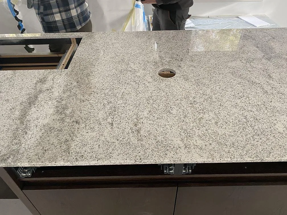 Polerad bänkskiva i Cotton White granit med urtag för diskho och blandare i ett kök i Höllviken.
