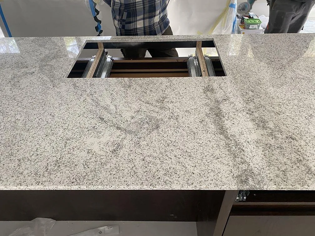 Polerad köksbänkskiva i Cotton White granit med urtag för häll, monterad i ett kök i Höllviken.