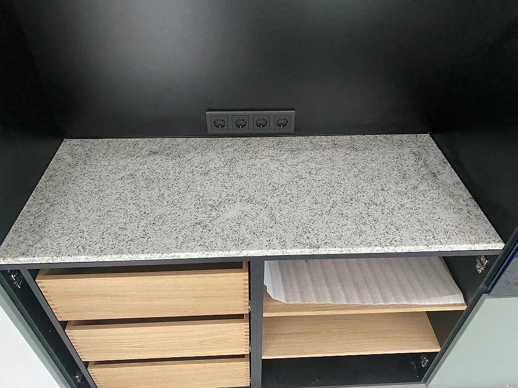 Köksbänkskiva i Cotton White granit ovanpå en bänkinredning med träinredning under montering i Höllviken.