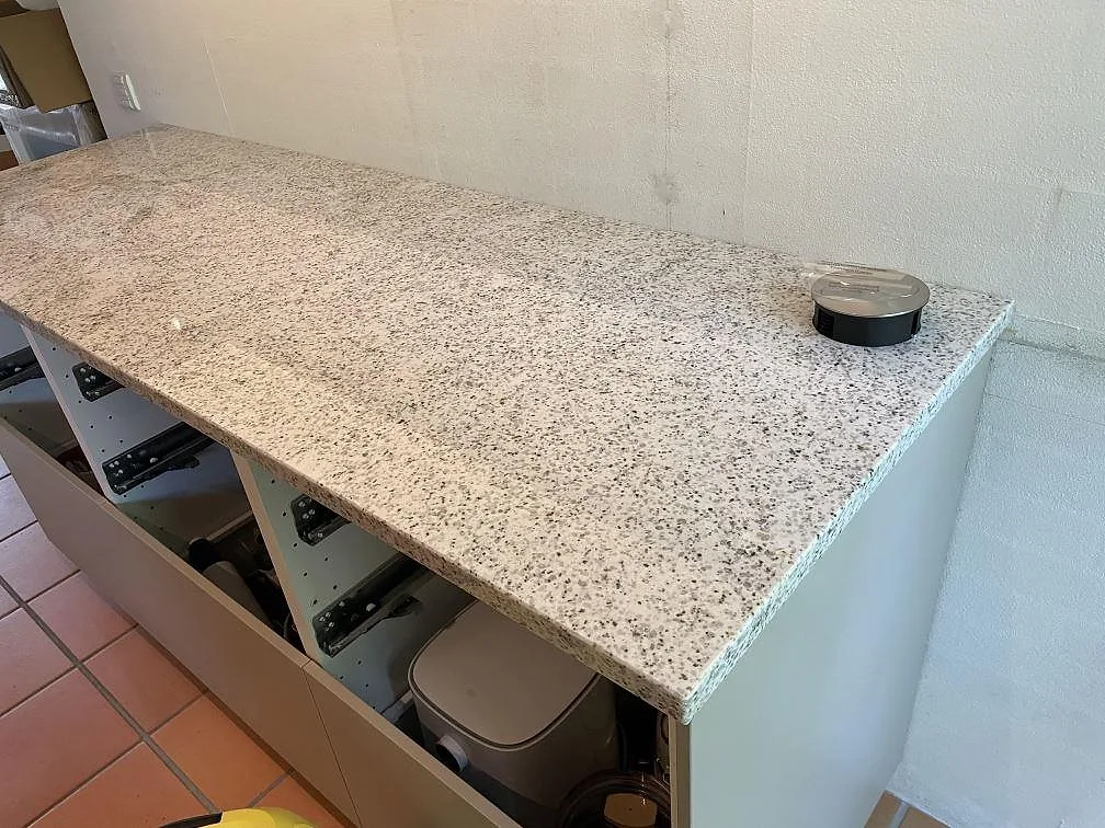 Installerad bänkskiva i polerad Cotton White granit på vita köksstommar med synlig ljus stenyta i Höllviken.