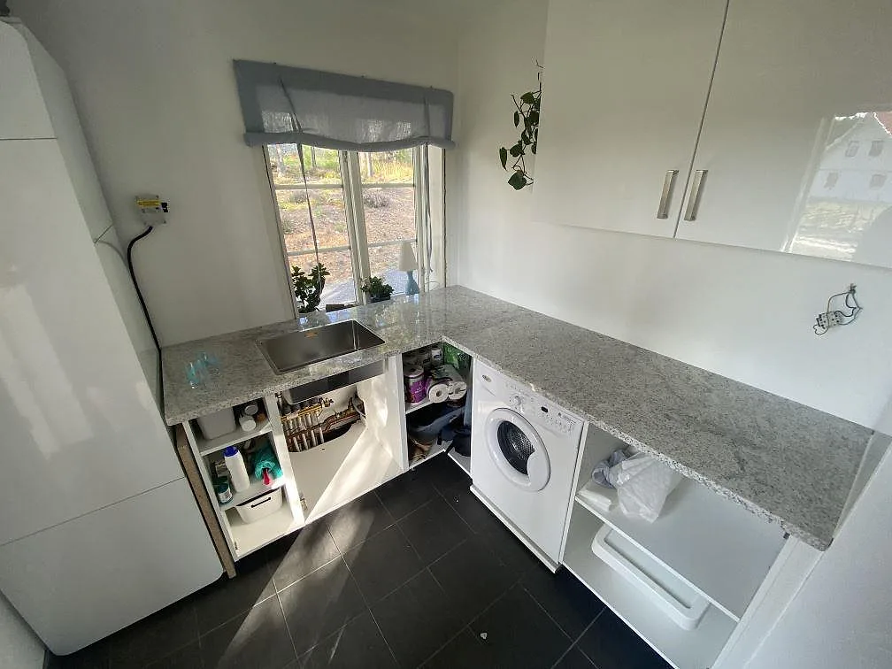 Bänkskiva i vit Cotton White-granit, polerad, med underlimmad rostfri diskho i ett grovkök i Vålberg, fotograferat under montering.