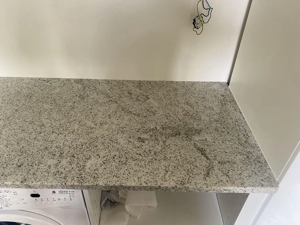 Polerad Cotton White-granit som bänkskiva ovanför tvättmaskinen i ett grovkök i Vålberg.
