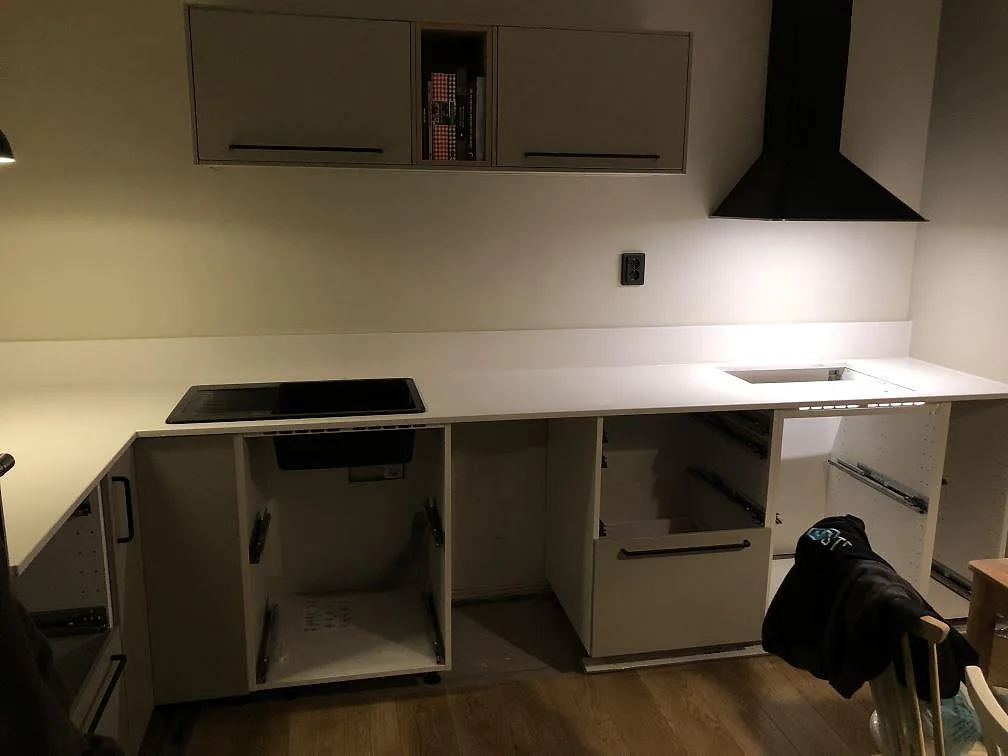 Bred polerad köksbänkskiva i vit Crystal Diamond kvartskomposit intill en svart häll i ett kök i Göteborg.