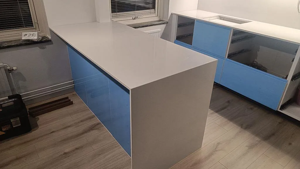 Polerad köksö och väggbänk i Crystal Diamond komposit i blått kök under montering i Malmö.