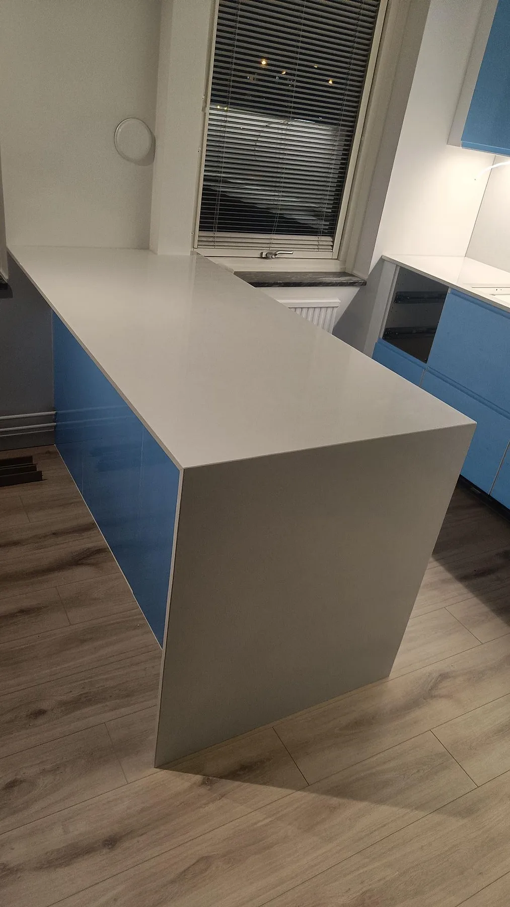 Köksö med bred bänkskiva i polerad Crystal Diamond komposit framför fönster i ett kök i Malmö.