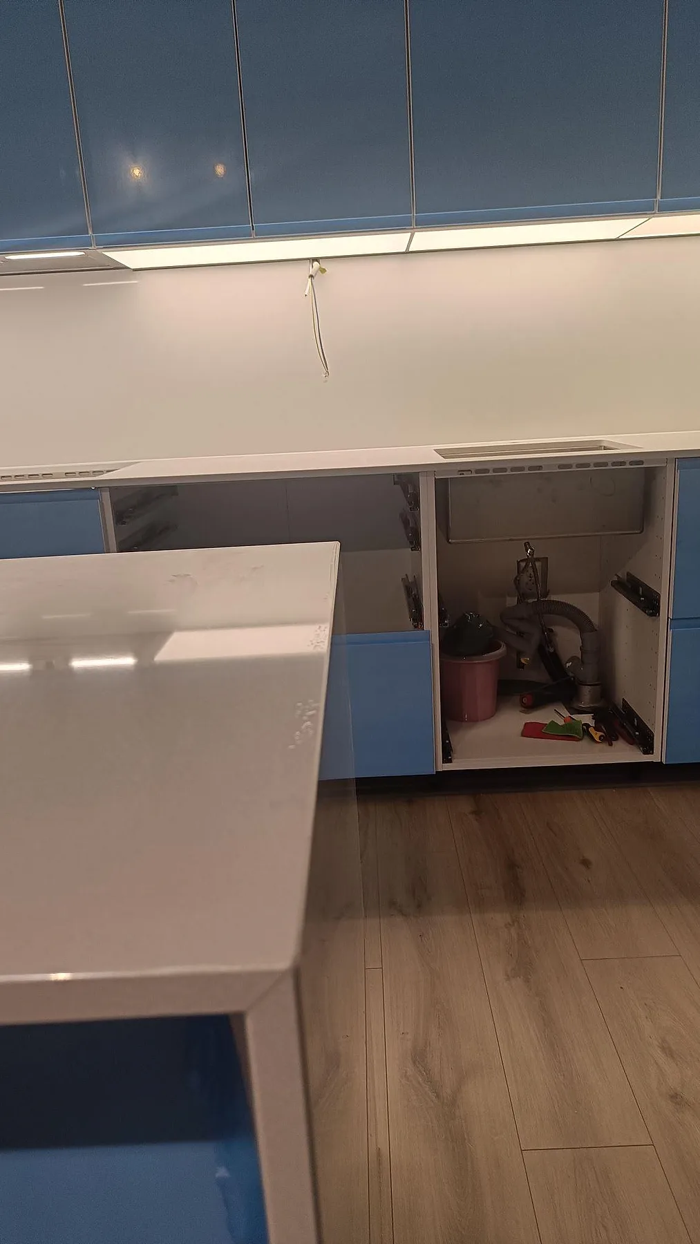 Installerad väggbänk och köksö i polerad Crystal Diamond komposit med öppna köksstommar under montering i Malmö.