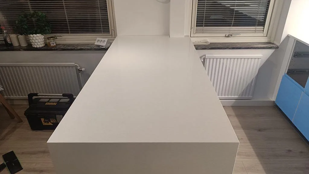 Ren köksö i polerad Crystal Diamond komposit med sammanhängande vit arbetsyta i ett kök i Malmö.