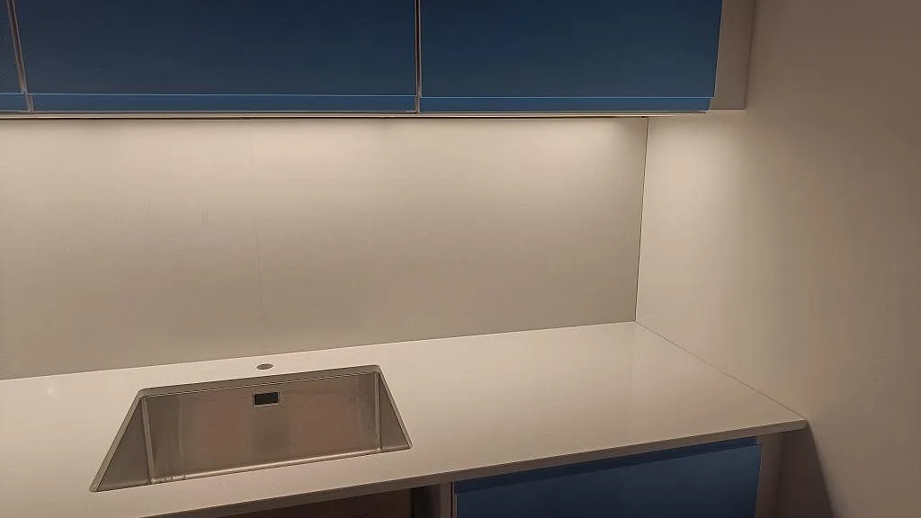 Köksbänkskiva i polerad Crystal Diamond komposit med rostfri diskho och ljus vägg i ett kök i Malmö.