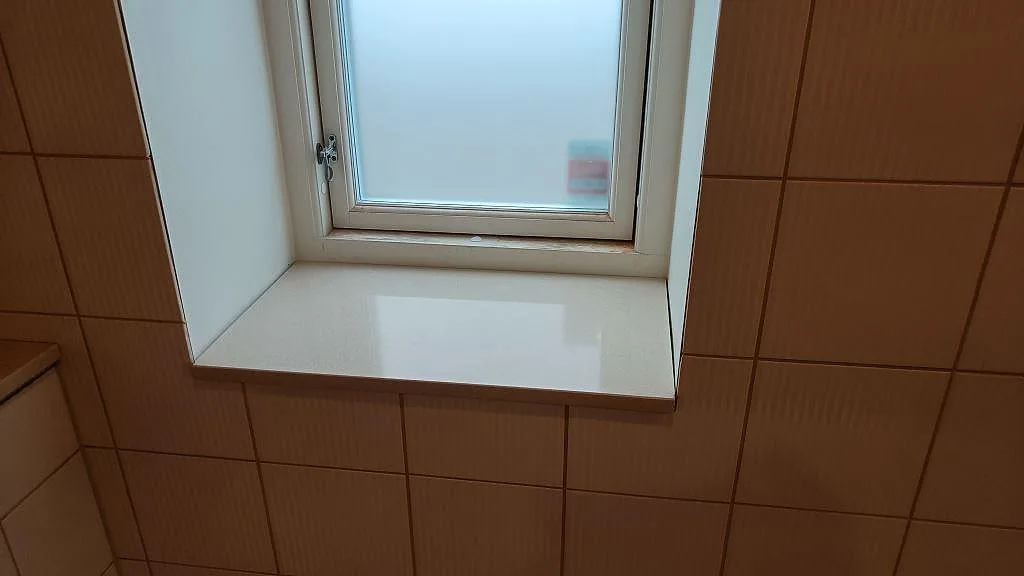 Fönsterbänk i polerad Crystal Royal komposit monterad i ett kaklat badrum i Trelleborg.