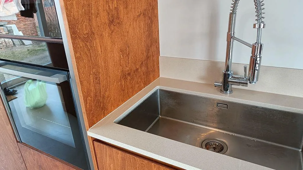 Köksbänkskiva i polerad Crystal Royal komposit med rostfri diskho och blandare i ett kök i Trelleborg.
