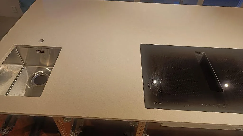Detalj av två diskhoar och svart induktionshäll i en polerad Crystal Royal köksbänkskiva i Trelleborg.