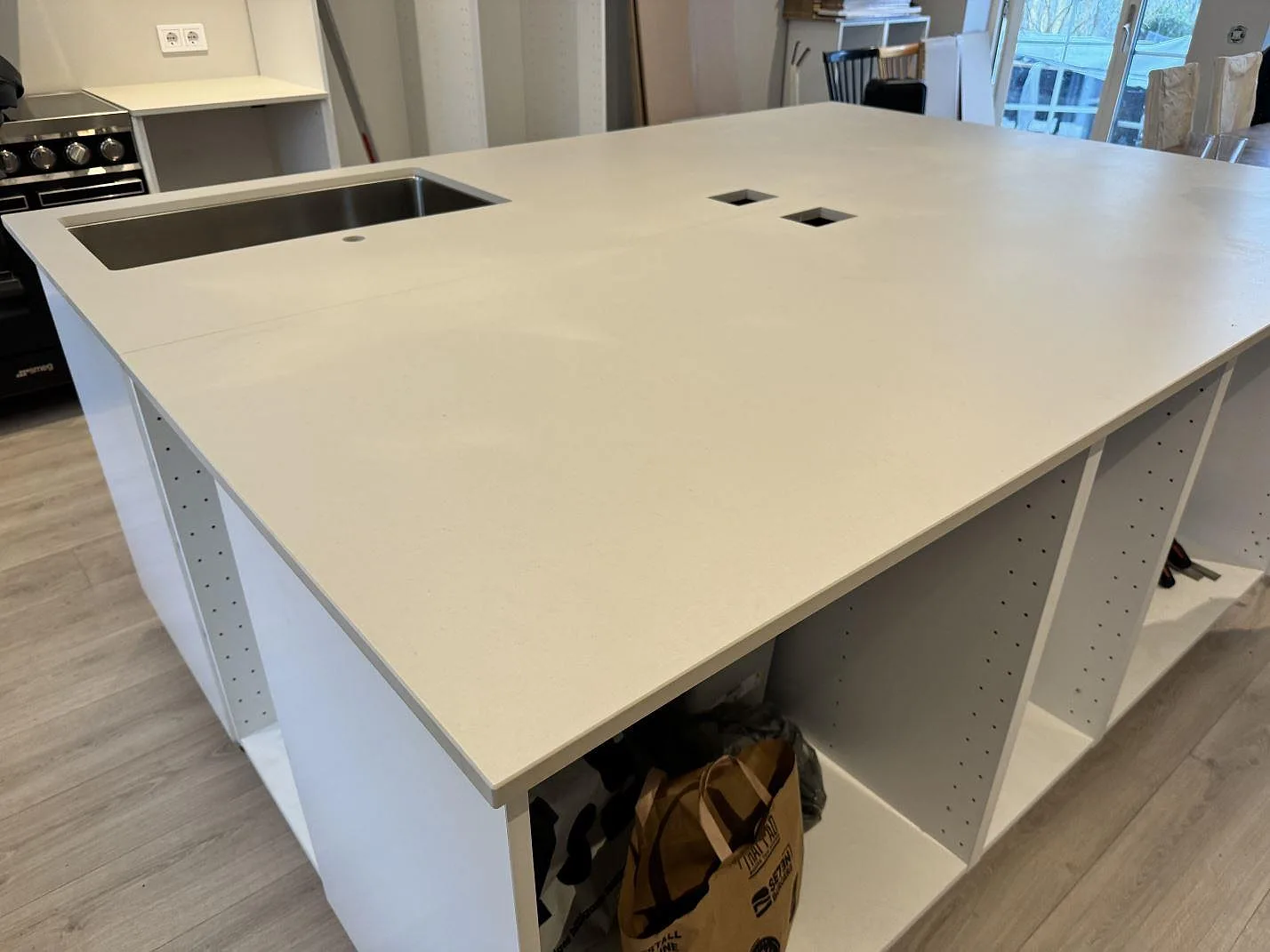 Installerad köksö i matt Dekton Aeris med bred arbetsyta och synliga vita köksstommar i Höllviken.