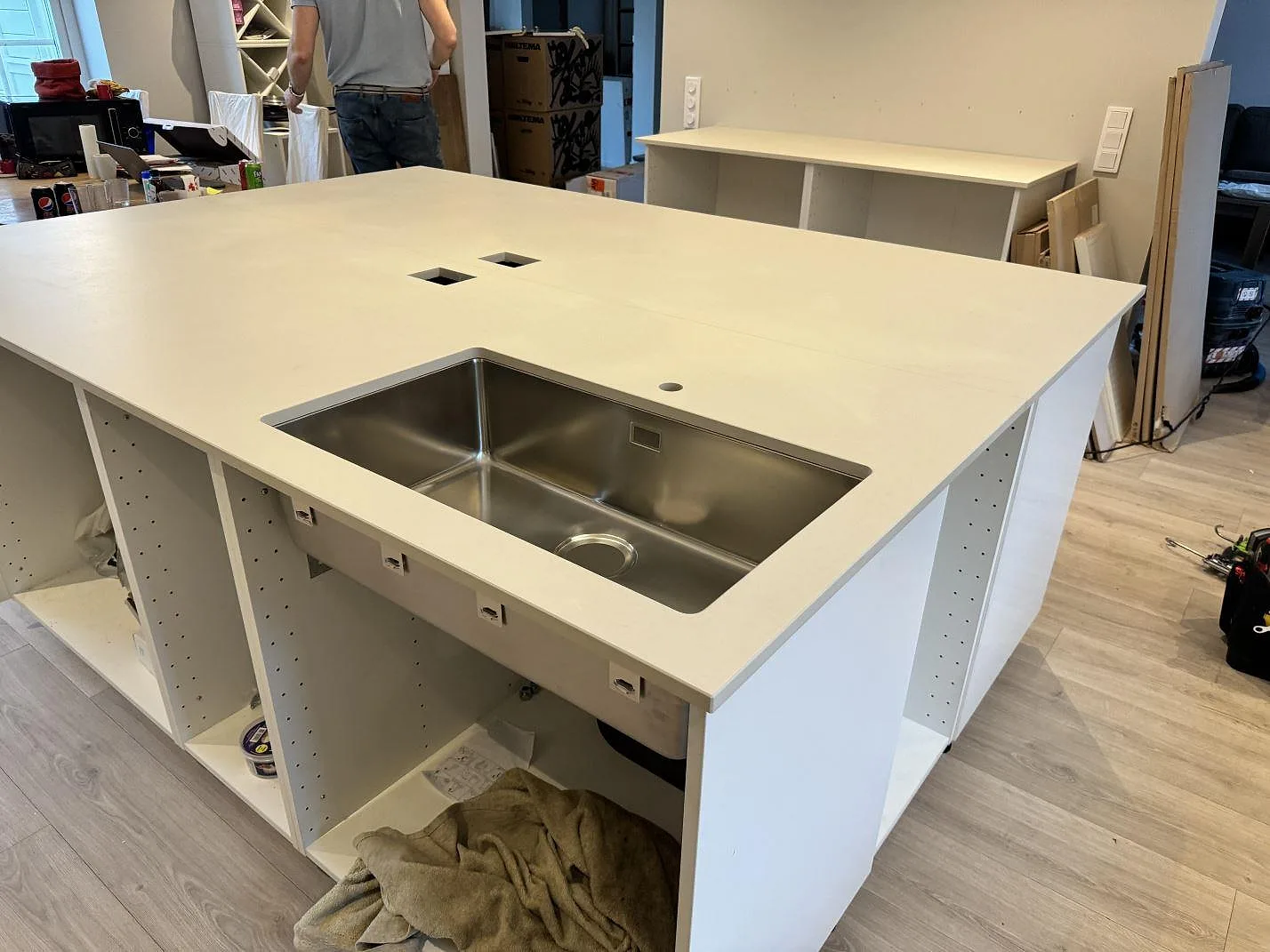Närbild på matt Dekton Aeris som köksö med underlimmad rostfri diskho och ljusa köksstommar i Höllviken.