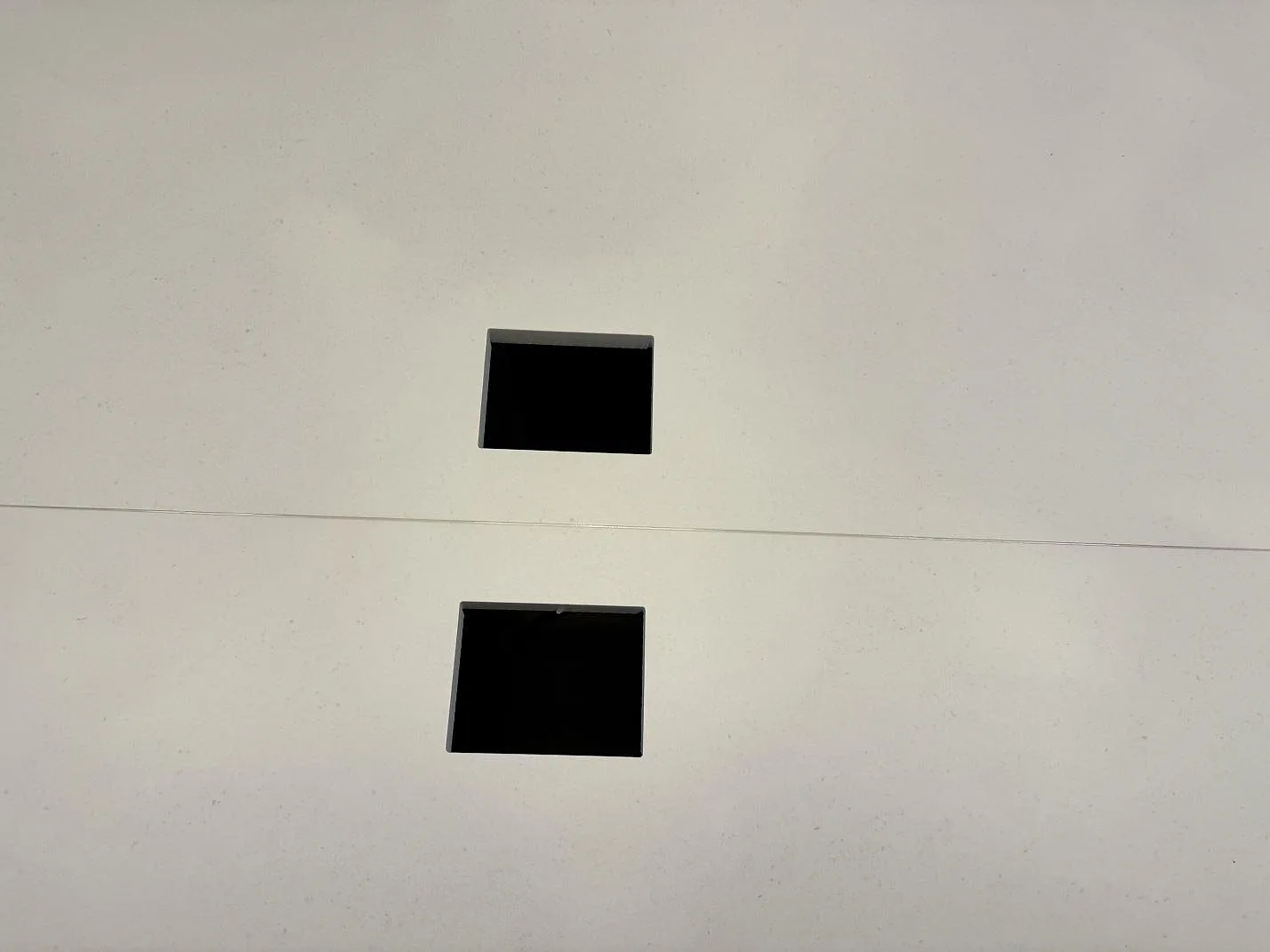 Detalj av två fyrkantiga urtag i matt Dekton Aeris på en installerad köksö i Höllviken.
