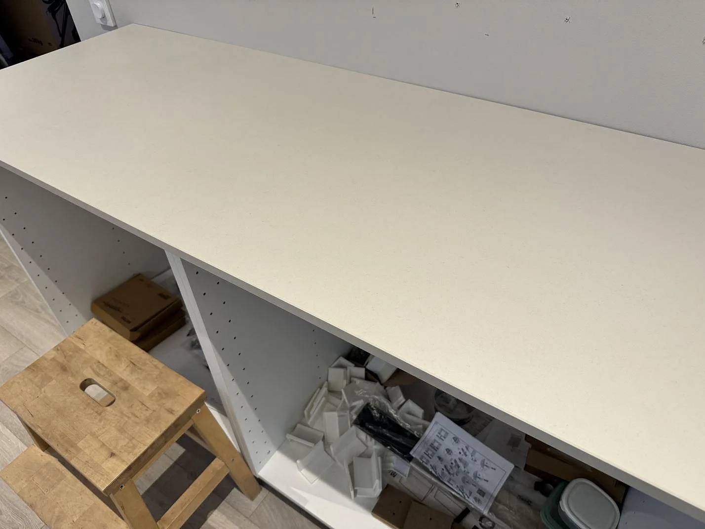 Sidobänk i matt Dekton Aeris längs vägg med vita köksstommar under montering i Höllviken.