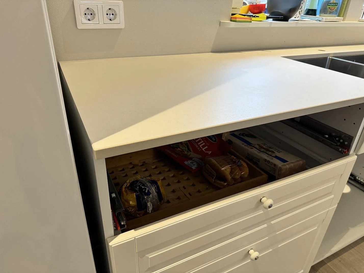 Matt Dekton Aeris bänkskiva vid diskbänk och lådor i ett vitt kök i Höllviken.