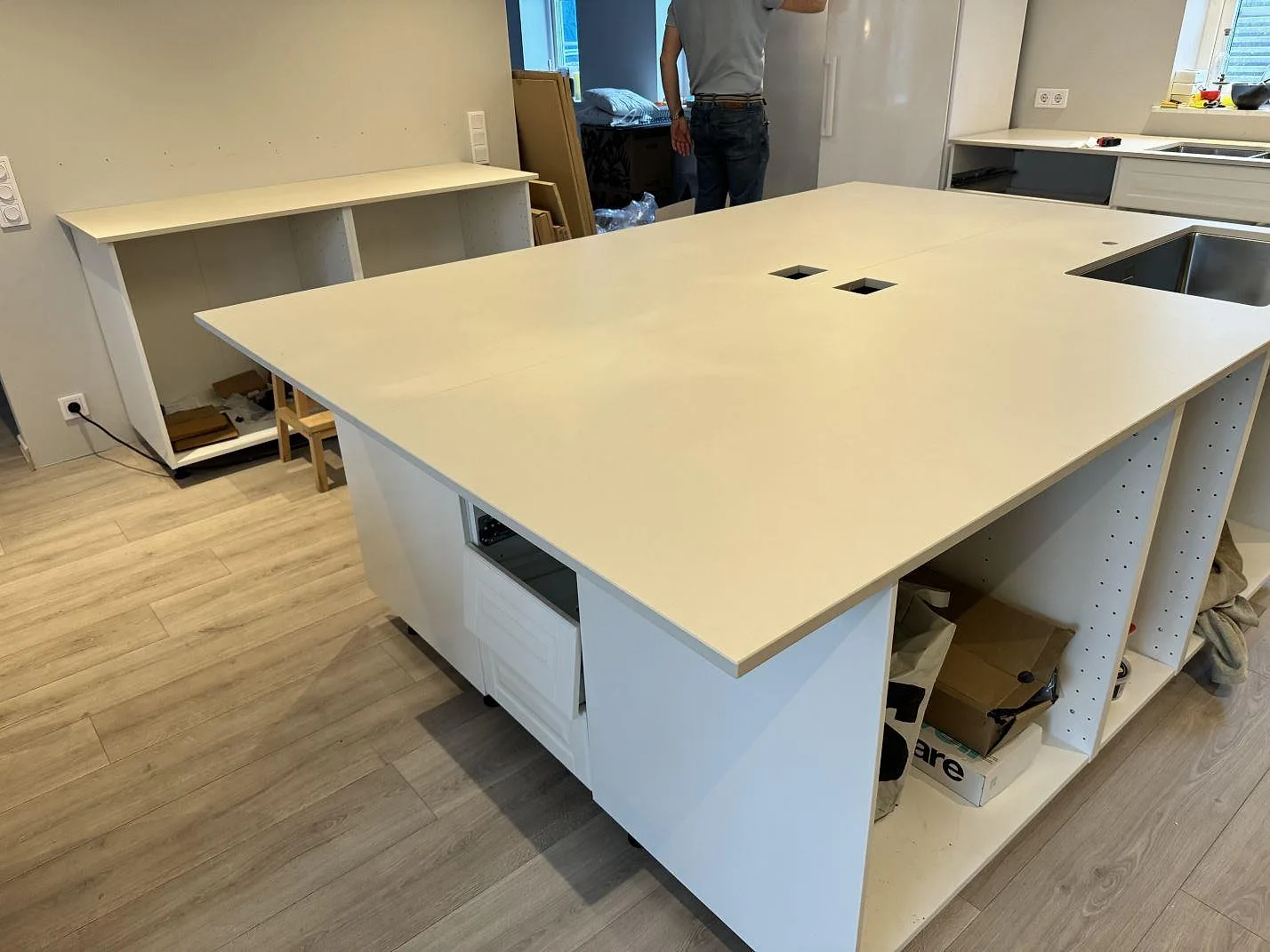 Köksbänkskiva i matt Dekton Aeris på stor köksö med vita köksstommar under montering i Höllviken.