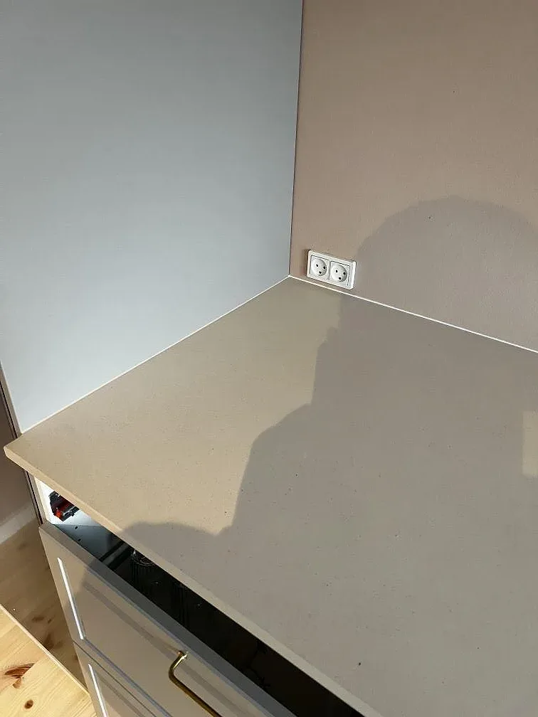 Hörnvy av köksbänkskiva i matt Dekton Aeris keramik med ljus väggyta och eluttag i Kgs. Lyngby.