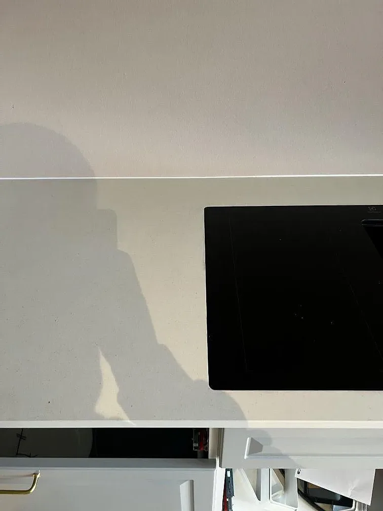 Detalj av matt Dekton Aeris bänkskiva runt svart induktionshäll och ljusa köksstommar i Kgs. Lyngby.